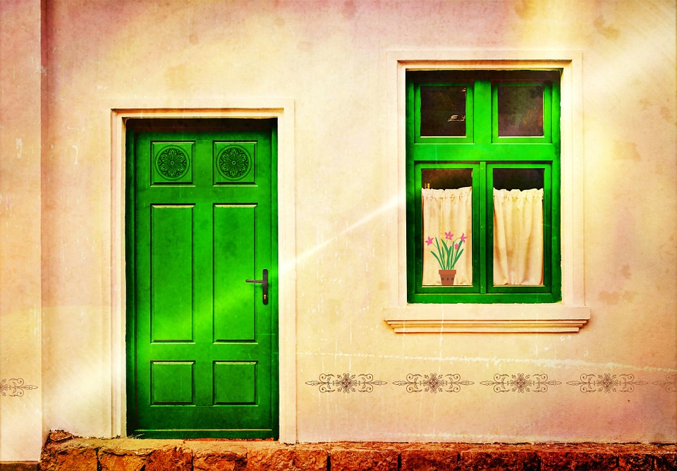 Hišna fasada z zelenimi vrati in oknom