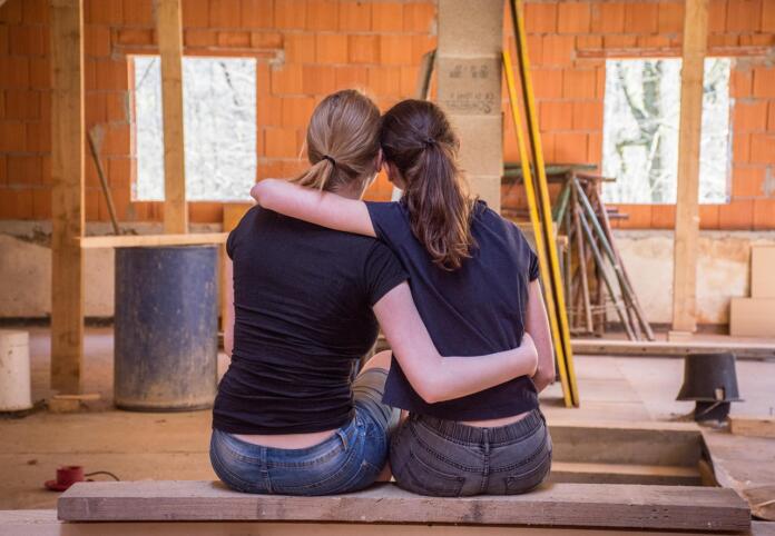 Dekleti se objemata v hiši v gradnji