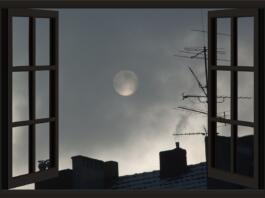 Odprta okna, vidi se luno in strehe hiš