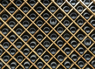 Vinarji, ste že prijavili zaloge vina? Wine bottles background. Bottles of red and white wine in a wine cabinet of a liquor store. High quality photo