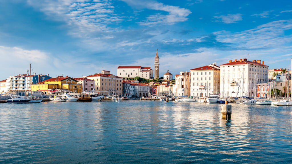 landscape view of Piran harbour and surrounding building and dwellings including tower and wharfs