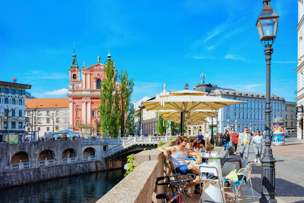 Ljubljana, Slovenia - April 27, 2018: People at sidewalk cafe on Triple bridge at Ljubljanica River in Ljubljana in Slovenia