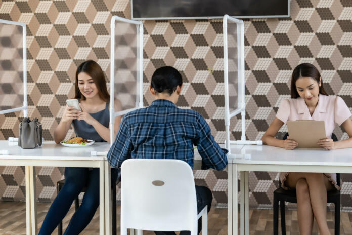 Restaurant customers have a seat with table shield partition for social distancing to reduce infection of coronavirus covid-19 pandemic. Restaurant new normal lifestyle.