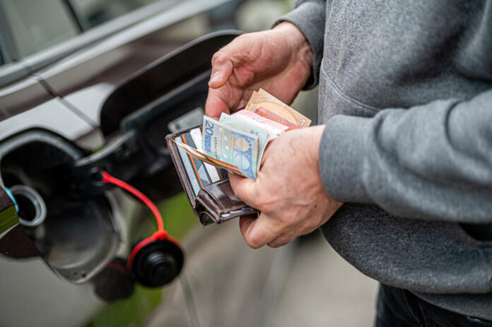 a man s hand counts money while standing at an open fuel tank, the concept of rising fuel prices