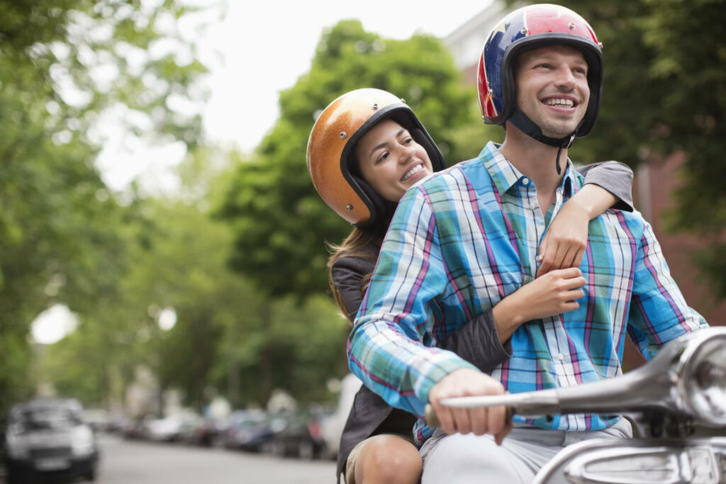 Couple riding scooter together outdoors