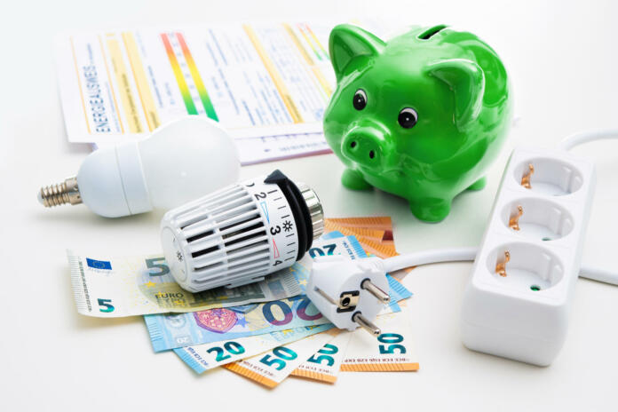 Energy cost, saving energy concept. Piggy bank with money, plug, bulb and radiator thermostat on white background