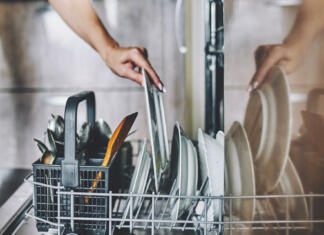 A woman's hand puts a dirty plate in the dishwasher