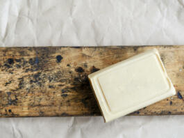 Briquette of laundry soap on an old wooden board. Demonstration of a single piece of new soap. Place for text. Natural hygiene products. Selective focus.