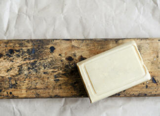 Iz odpadnega pepela izdelajte milo ali učinkovito čistilno pasto Briquette of laundry soap on an old wooden board. Demonstration of a single piece of new soap. Place for text. Natural hygiene products. Selective focus.