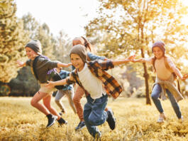 Skupina otrok se smeji in teče po travi