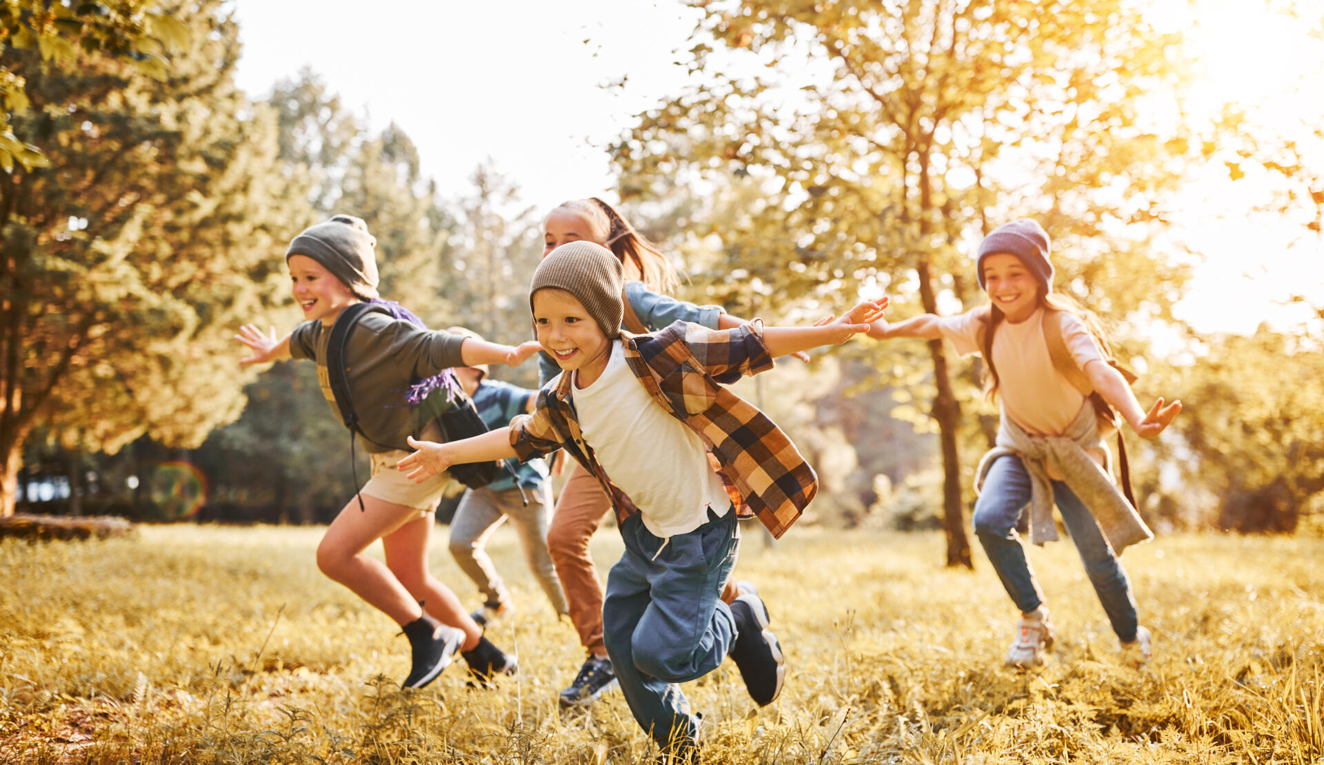 Skupina otrok se smeji in teče po travi