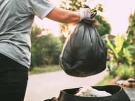 hand holding garbage black bag putting in to trash