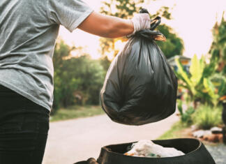 Kam sodi odpadek: med odpadno embalažo, mešane ali biorazgradljive odpadke? hand holding garbage black bag putting in to trash