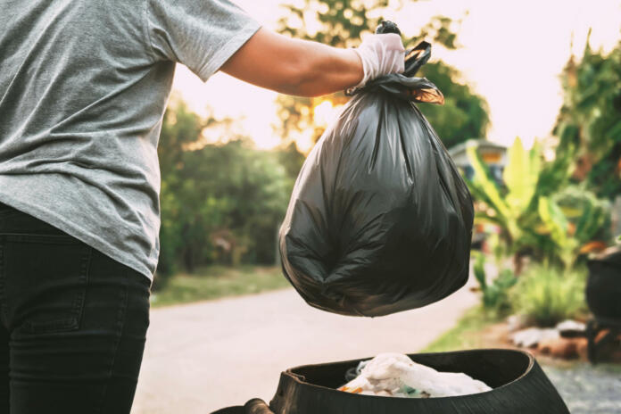 hand holding garbage black bag putting in to trash