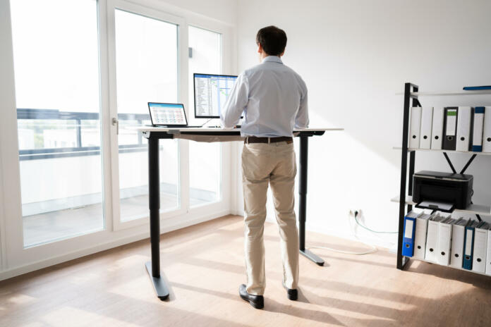 Man Working On Computer At Standing Desk In Home Office