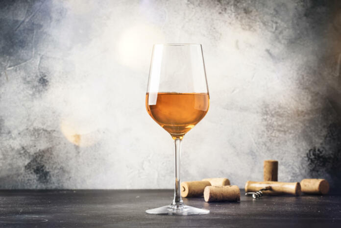 Orange wine in big wine glass, fashionable modern drink, gray counter background, copy space, selective focus