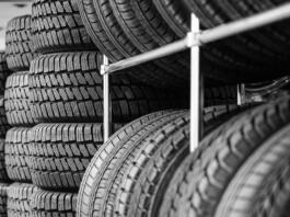 Rack with variety of new car tires in automobile store, selective focus