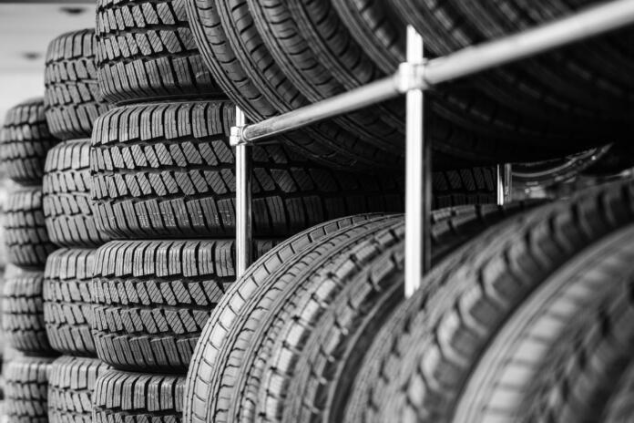 Rack with variety of new car tires in automobile store, selective focus