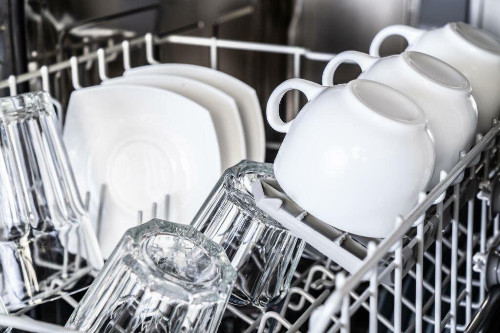 White cups in new dishwasher close-up. Clean dishes. Housekeeping devices.