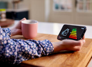 Ukrepi za energetsko bolj učinkovit in trajnosten dom Close Up Of Woman Holding Smart Energy Meter In Kitchen Measuring Energy Efficiency