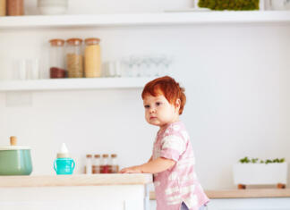 Idealna višina kuhinjskega pulta cute toddler baby climbs on step stool, trying to reach things on the high desk on the kitchen