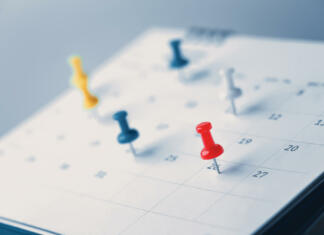 Dela prosti dnevi v 2023: Dopusti in dodatnih 11 dni doma Embroidered red pins on a calendar event Planner calendar,clock to set timetable organize schedule,planning for business meeting or travel planning concept.