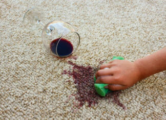 3 triki za odstranjevanje vinskih madežev (Kako odstraniti rdeče vino iz oblačil?) Glass of red wine fell on carpet. Female hand cleans floor with sponge and detergent.