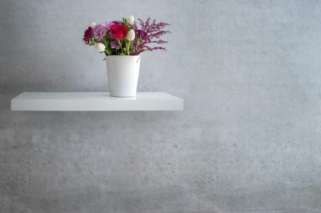 Spring flowers on floating white shelf against concrete wall design