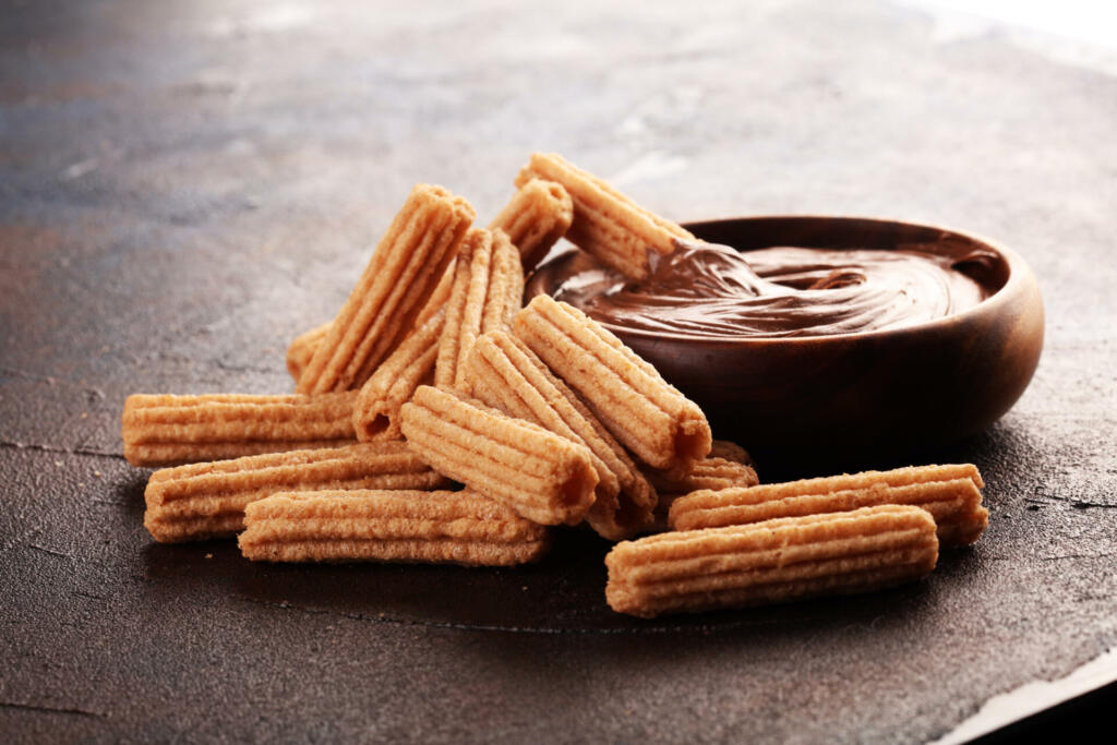 Traditional Spanish dessert churros with sugar and chocolate.