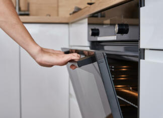 Kateri krožnik gre lahko v pečico? Woman hand open electric oven door with handle. Homemade cooking. Kitchen appliance