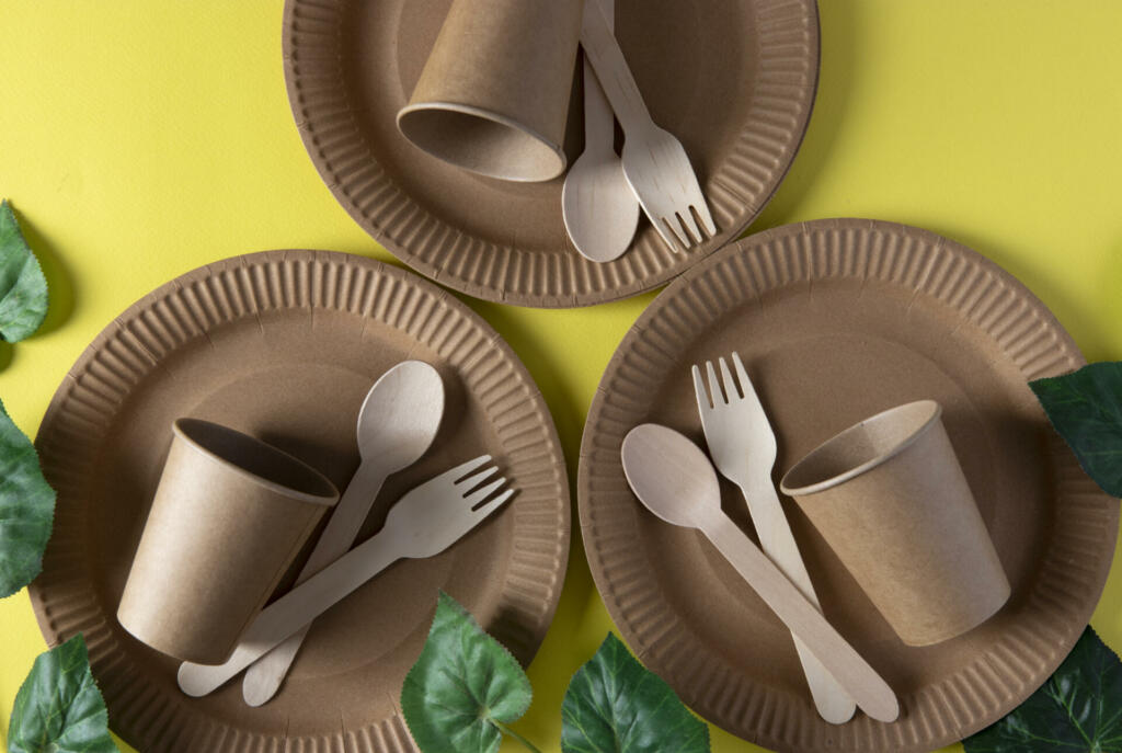 Wooden forks and spoons, eco friendly disposable kitchenware utensils on yellow background. Zero waste concept. View from above