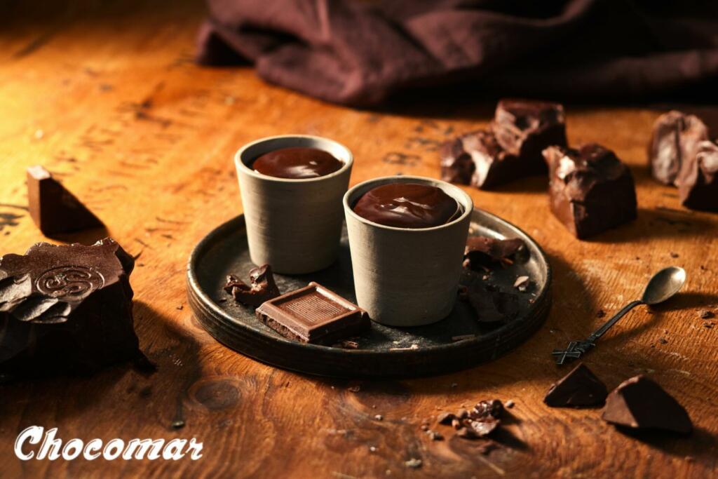 Skodelici vroče čokolade na pladnju, poleg so kosi temne čokolade