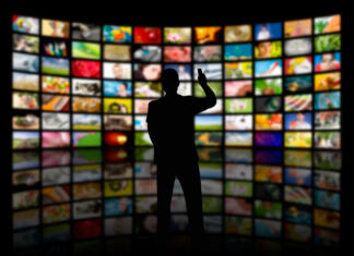 Back view of a young man watching a big TV panel