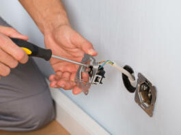 Close-up Of Electrician Hands With Screwdriver Installing Wall Socket