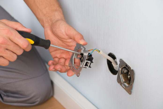 Close-up Of Electrician Hands With Screwdriver Installing Wall Socket