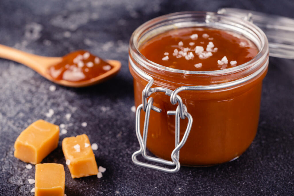 Glass jar with tasty delicious salted caramel, selective focus