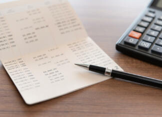 Prijava računa v tujini: Kako prijaviti račun v tujini? home finance concept. pen ,bank book account and calculator on desk.