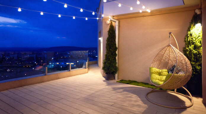 cozy rooftop terrace with rattan hanging chair, garlands and beautiful landscape at night