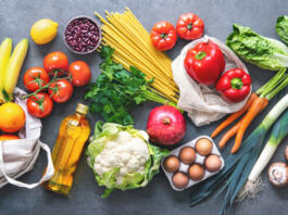 Groceries shopping. Flat lay of fruits, vegetables, greens, bread and oil in eco friendly bags, top view. Healthy eating and sustainability concept