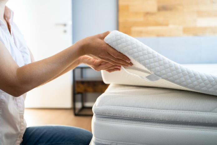 Mattress Topper Being Laid On Top Of The Bed