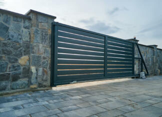 Vrste vrtnih ograj: prednosti in slabosti Wide automatic sliding gate with remote control installed in high stone fense wall. Security and protection concept.