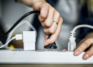 Prepolovite račun! Naprave, ki porabijo največ elektrike, izklopite jih vsaj čez noč Woman plugging the wire to the outlet