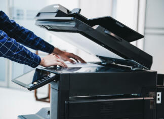 Najem tiskalnika je odlična izbira namesto nakupa Copier printer, Close up hand office man press copy button on panel to using the copier or photocopier machine for scanning document printing a sheet paper.