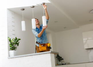 Razsvetljava doma: Kako izbrati primerno jakost svetlobe za vsak prostor Electrician is installing and connecting a lamp to a ceiling.