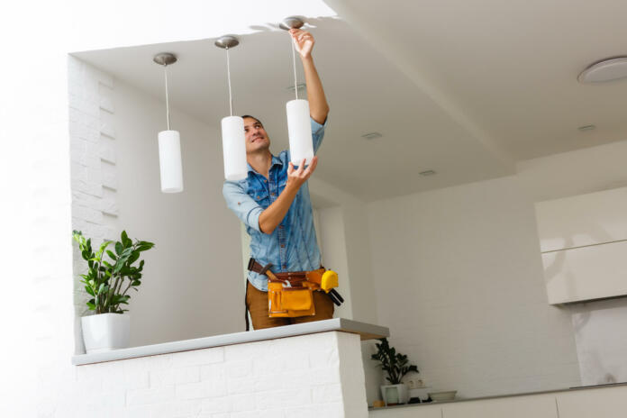 Electrician is installing and connecting a lamp to a ceiling.