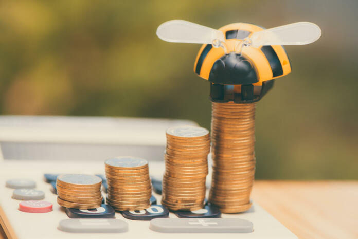 Savings, Growing coins and calculator on wood table with bee toy on green tree bokeh background vintage tone.  business finance wealth and success concept.