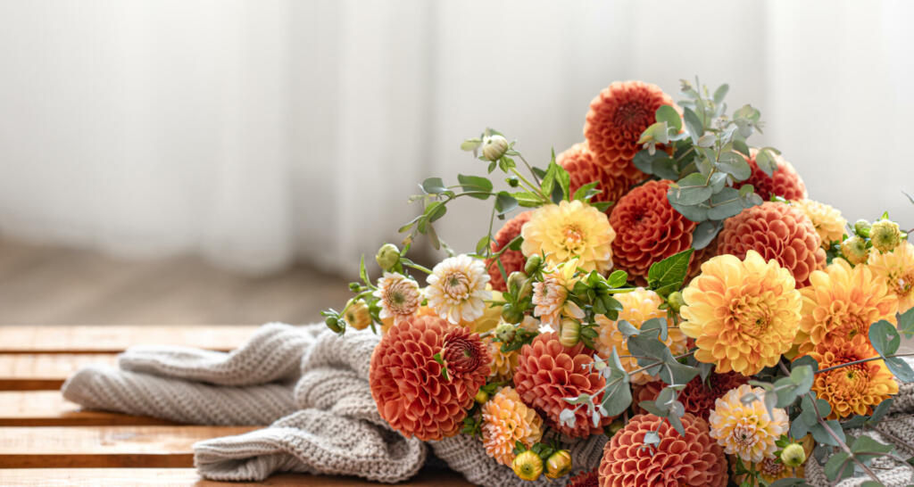 A bouquet of yellow and orange chrysanthemums and a knitted element on a blurred background, copy space.