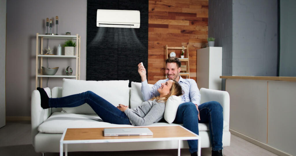 Happy Family Couple Using Air Conditioner. Apartment AC