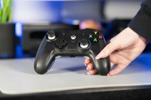 Ipswich, United Kingdom – October 24, 2022: A girl's hand holding a black nacon xbox controller with painted finger nails