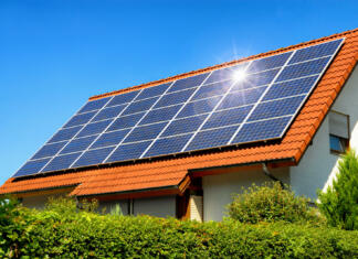 5 glavnih prednosti domače sončne elektrarne Solar panel on a red roof reflecting the sun and the cloudless blue sky
